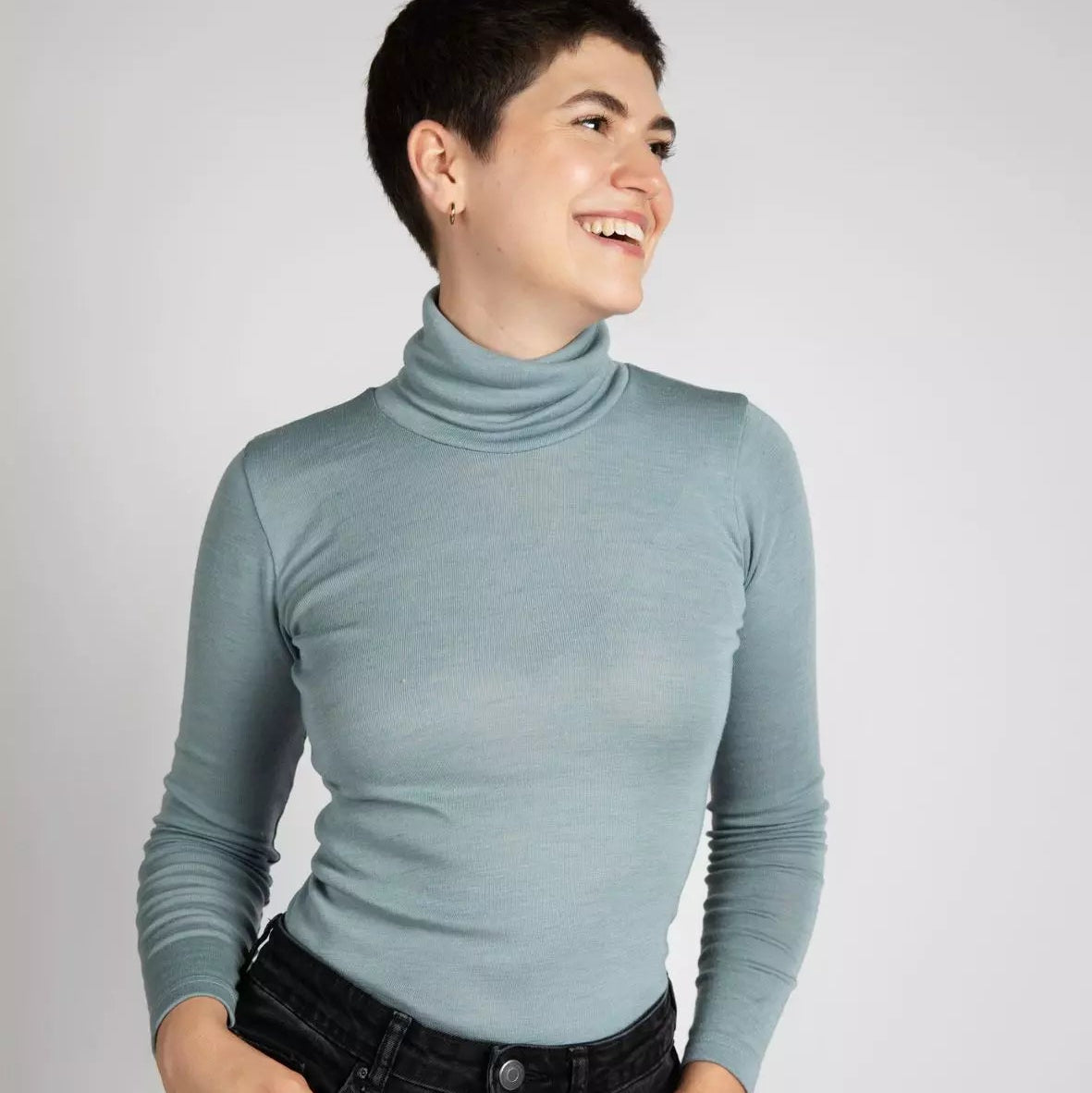 Person wearing a light blue turtleneck sweater against a plain background
